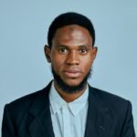 Portrait of a man in a suit and shirt against a neutral background, conveying professionalism.